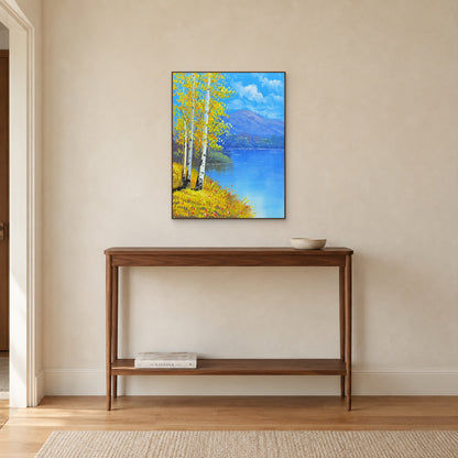 Birch lakeshore painting in a walnut-toned frame above a narrow wooden console on a warm wall.