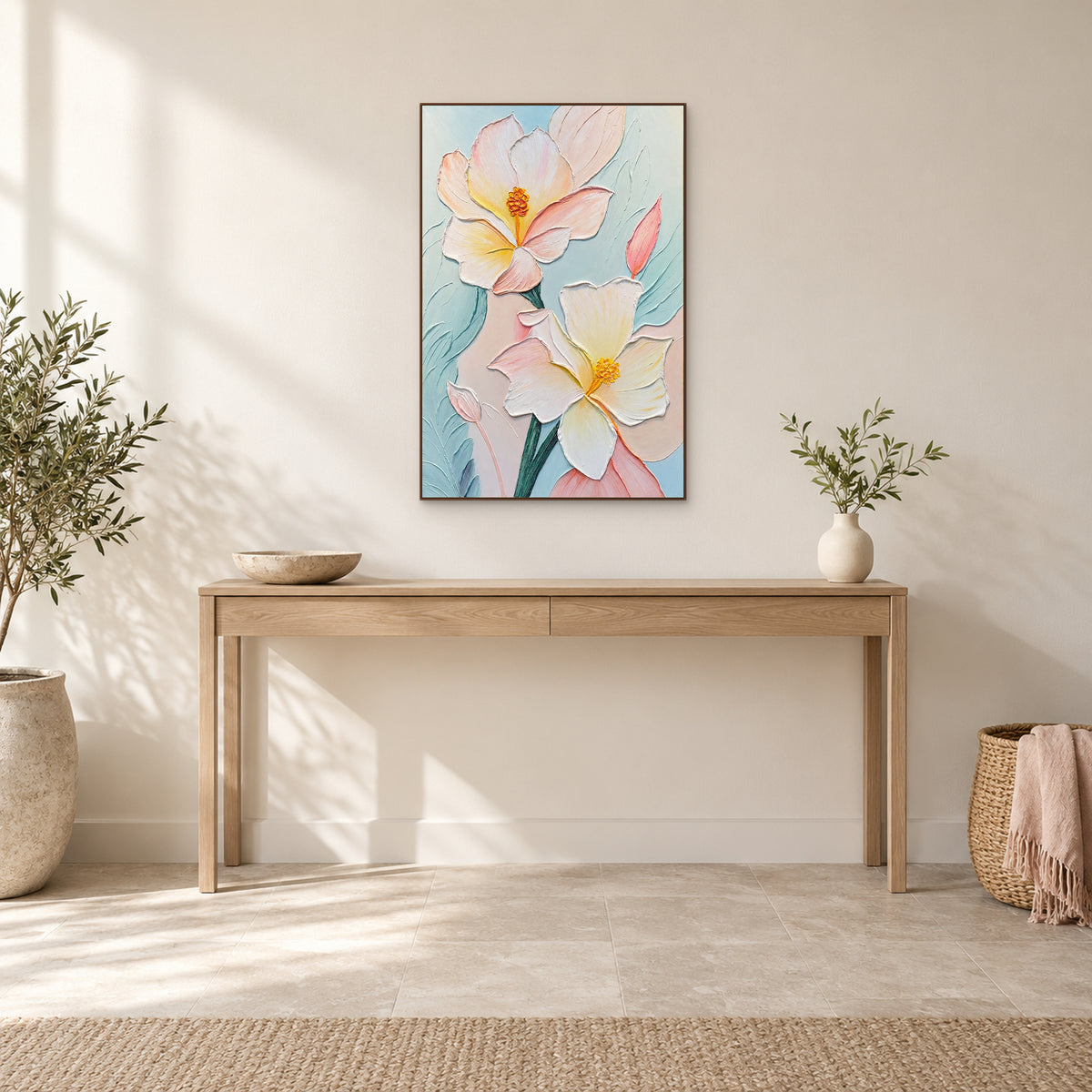 Two large pale flowers in a walnut-coloured frame above an oak console with a stone bowl and ivory vase