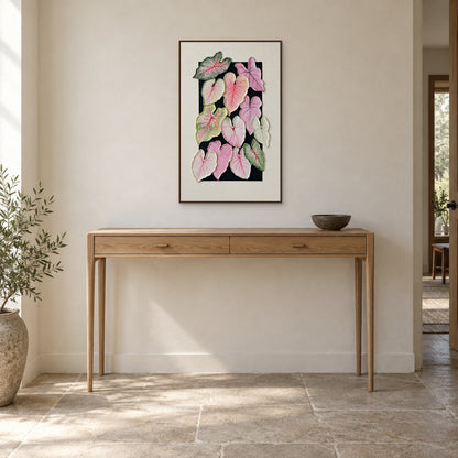 Vertical caladium painting in a walnut-tone floating frame above a light oak entryway console