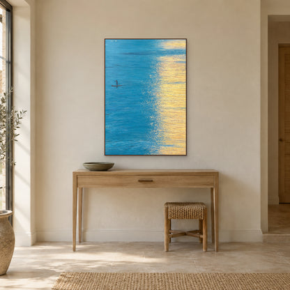 Quiet boat seascape in a walnut-tone floating frame above a light oak entry console