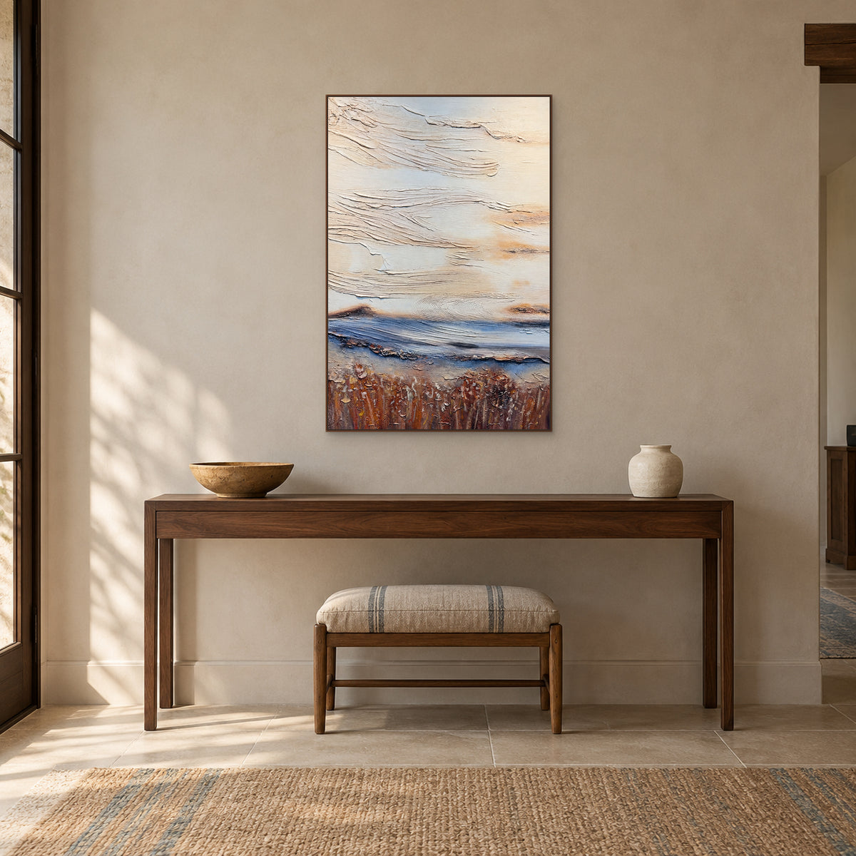 Blue and ochre abstract in a walnut-coloured frame above a dark console with a bowl, vase and striped stool