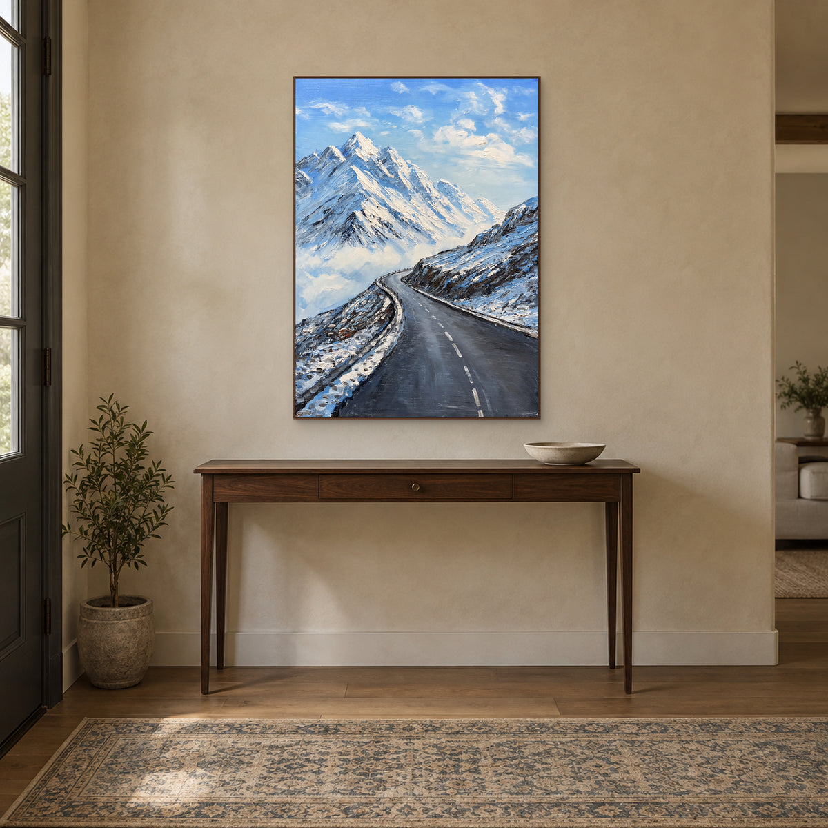 Textured mountain road painting in a walnut-tone floating frame centred above a wooden entryway console
