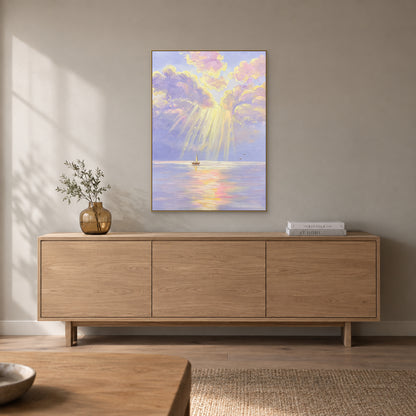 Pastel seascape in a champagne-tone frame above a pale wooden sideboard with a small amber vase and books.
