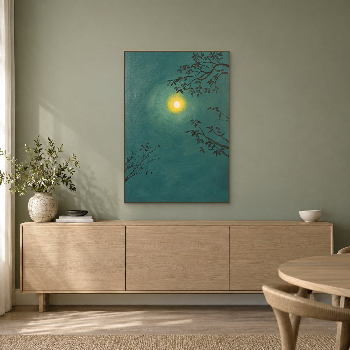 Green moon and branches painting in a champagne-tone frame above an oak-toned sideboard