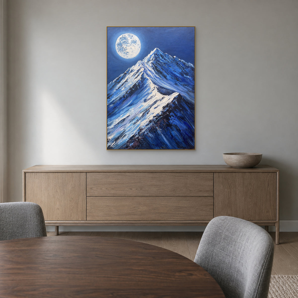 Blue snow mountain painting in a champagne-tone frame above a wooden dining-room sideboard