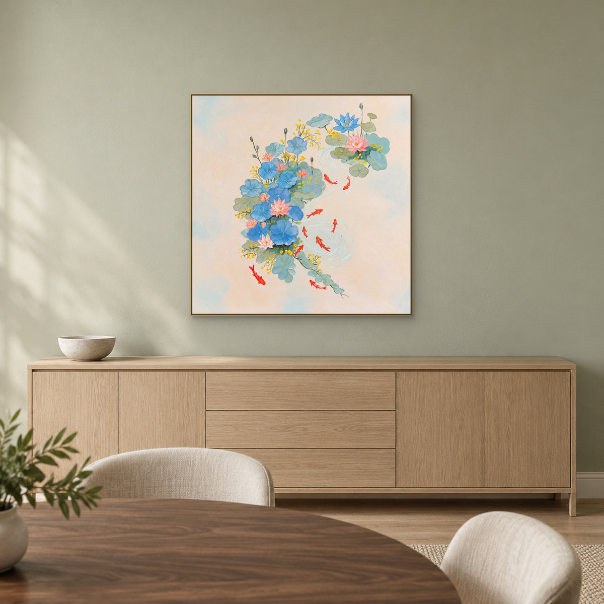 Square red koi and blue lotus painting in a champagne-toned frame above an oak-toned dining sideboard