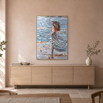 Woman beside the sea in a champagne-toned floating frame above a pale oak-toned sideboard against a blush-beige wall