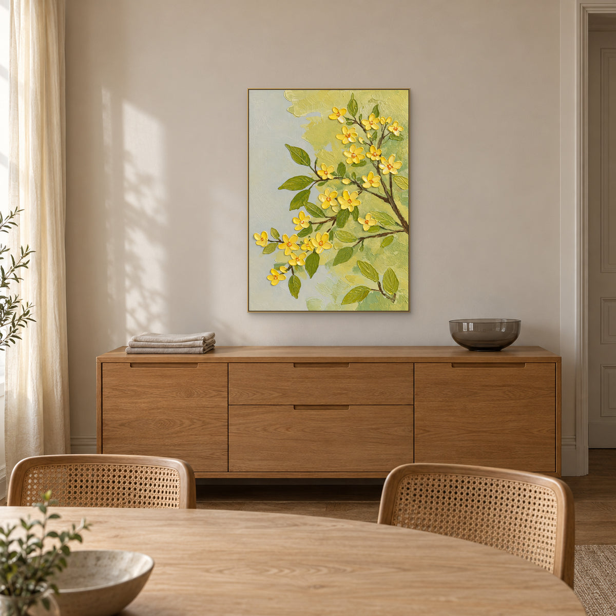 Champagne-framed yellow blossoms above an oak-tone sideboard, with woven dining chairs in the foreground