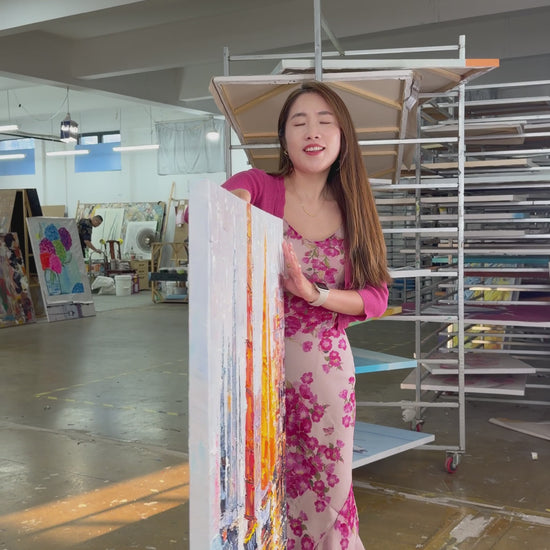 Supplier holds and turns a textured harbour painting with orange and golden sails