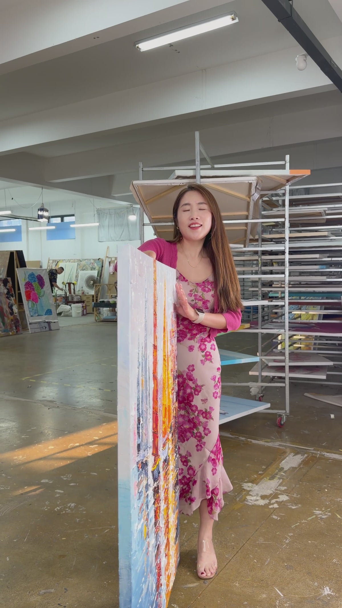 Supplier holds and turns a textured harbour painting with orange and golden sails