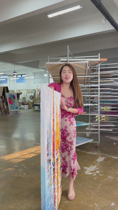 Supplier holds and turns a textured harbour painting with orange and golden sails
