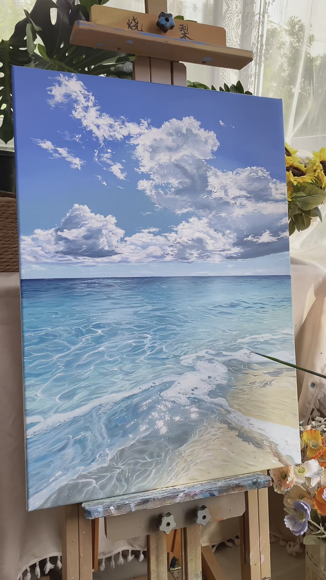 Real studio video showing the finished blue seascape, cloud and water brushwork, and the completed painting on an easel